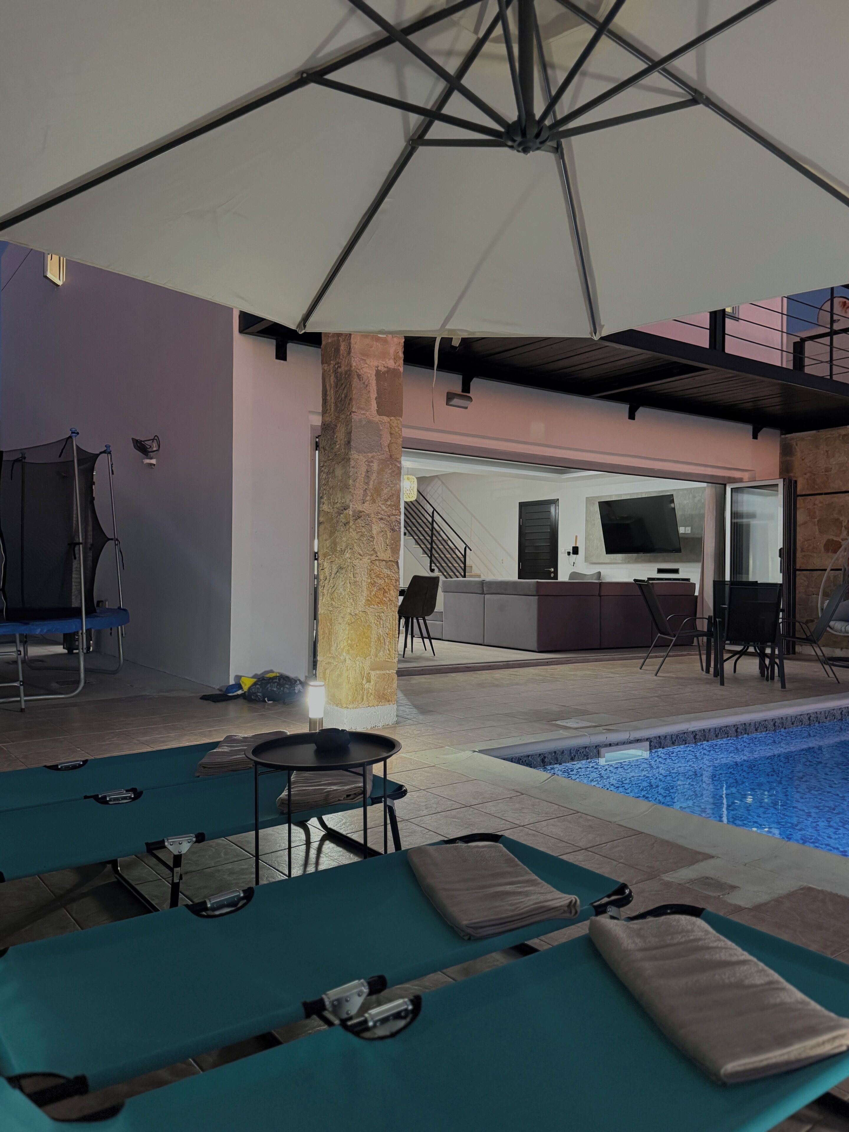Un espace piscine intérieure avec des chaises longues, une table et un bar en arrière-plan.