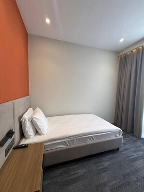 Una cama individual con cabecera, una mesita de noche y un control remoto encima.