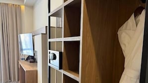 A hotel room with a wooden wardrobe, a desk, and a television.