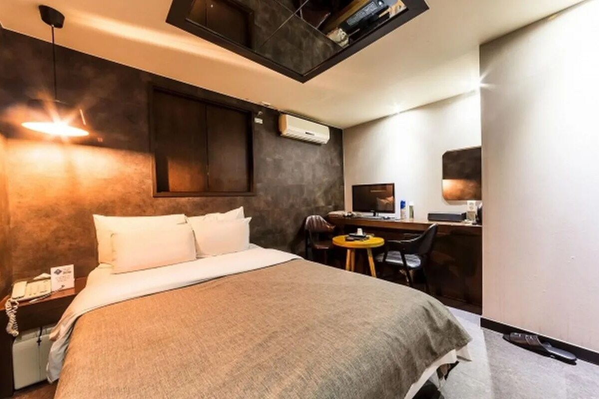 Een hotelkamer met een bed, nachtkastje, bureau, stoel en een klein rond tafeltje.