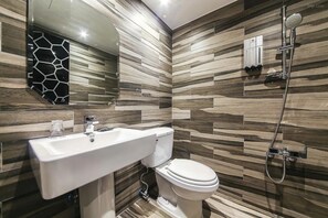 Een moderne badkamer met een grote spiegel, een witte wastafel, een toilet en een douche met een handdouche.