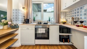 Cocina compacta con lavavajillas, horno, microondas y ventana con cortinas.