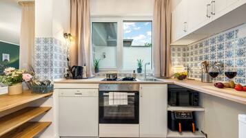 Eine kleine Küche mit Geschirrspüler, Backofen, Mikrowelle und einem Fenster mit Vorhängen.
