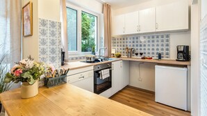 Una cocina moderna con armarios blancos, encimera de madera, un fregadero, estufa y refrigerador.