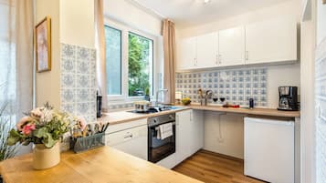 Eine moderne Küche mit weißen Schränken, einer Holz Arbeitsplatte, einer Spüle, einem Herd und einem Kühlschrank.