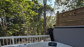 Jacuzzi con terraza de madera y barandilla blanca, rodeado de árboles.