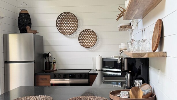 Una cocina moderna con una isla central, sillas de madera, un refrigerador de acero inoxidable y un microondas.