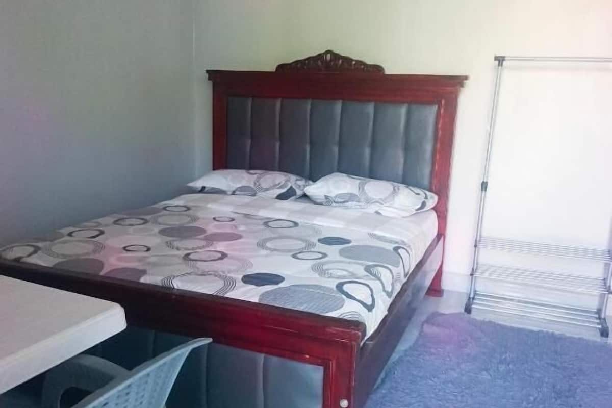 Een slaapkamer met een bed, een tafeltje, een stoel en een radiator.