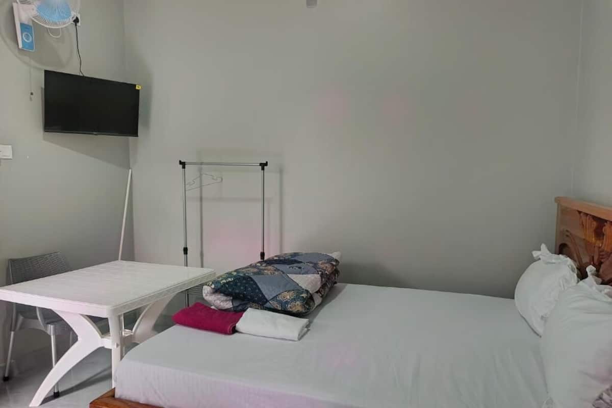 Een slaapkamer met een bed, bureau, stoel, televisie aan de muur en een radiator.