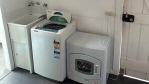 A laundry area with a washing machine, dryer, and a cabinet. - Stay on pinks beach road, 500m walk to pinks beach (Pinks Beach)