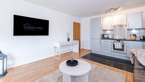 Une cuisine moderne avec des meubles blancs, un four à micro-ondes et une machine à café.