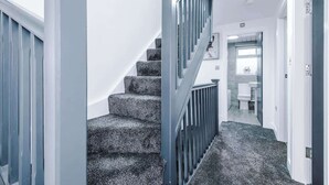 A staircase with a handrail, leading to a bathroom with a toilet and a sink. - 3BR Elegant House in Leeds | Sleeps 6 | Driveway (West Yorkshire)
