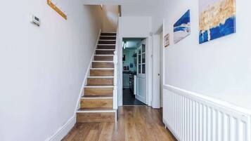A hallway with a wooden staircase, white walls, and a radiator.