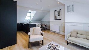 Een moderne woonkamer met een bank, een eettafel en een keukenhoek met een raam.