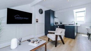 Een moderne woonkamer met een flatscreen televisie, een eethoek, een keukeneiland en een kleine keuken.