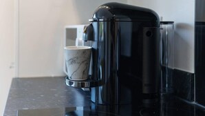 Una macchina da caffè su un piano di lavoro nero con una tazza di marmo accanto.