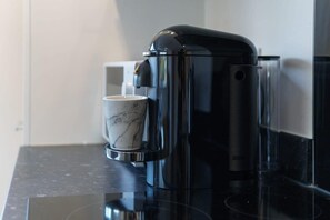 A coffee machine on a black countertop with a marble cup beside it. - Spacious Salford Quays Apartment, Prime Location (Greater Manchester)