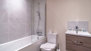 Un bagno moderno con doccia vetrata, un water bianco e un mobile lavabo con articoli da toilette.