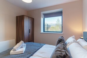 Ein Schlafzimmer mit Bett, Fenster mit Blick, Kleiderschrank und Nachttisch.