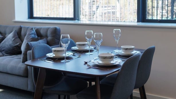 Zona pranzo con tavolo apparecchiato per quattro persone, quattro bicchieri da vino e quattro piatti.