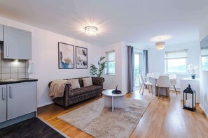 Un salon moderne comprenant un canapé, une table basse et un coin repas avec des chaises et une table.