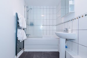Une salle de bain moderne avec une douche à parois de verre, un lavabo blanc et un porte-serviettes.
