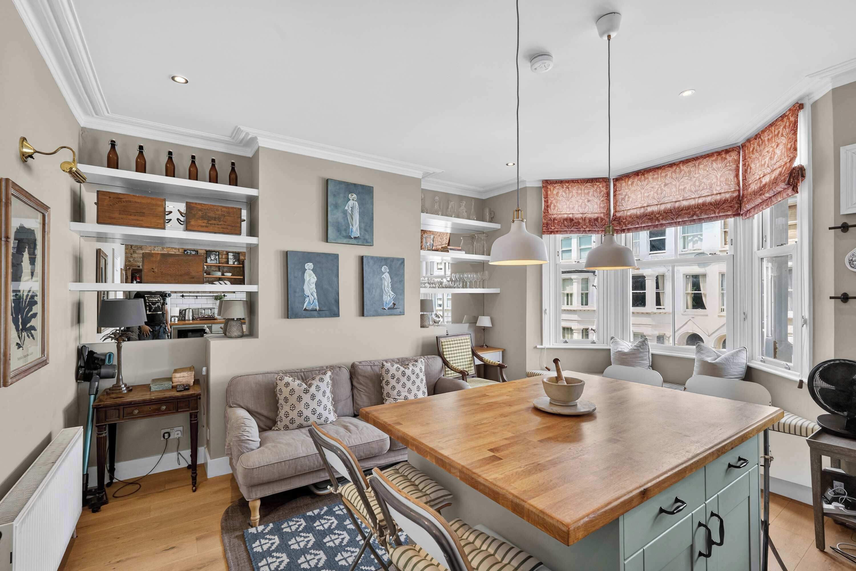 A modern kitchen with a central island, built-in shelves, and a dining area with a sofa.