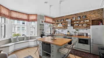 A modern kitchen with a built-in island, white cabinetry, and a stone accent wall.
