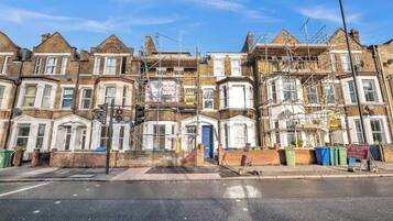 A row of terraced houses under construction with scaffolding, a traffic light, and a 'Do Not Overtake Cyclists' sign.