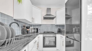 Una cocina moderna con gabinetes blancos, una campana extractora de acero inoxidable, horno integrado y microondas.