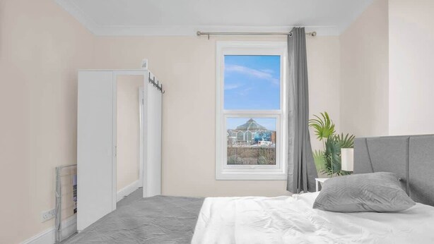 Un dormitorio con cama, ventana con vistas, puerta y planta.