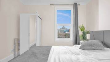 A bedroom with a bed, a window with a view, a door, and a plant.