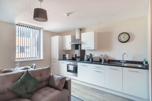 A modern kitchen with white cabinets, a black countertop, and a stainless steel sink. - Apartment for 2 | Salford | All Amenities (Greater Manchester)