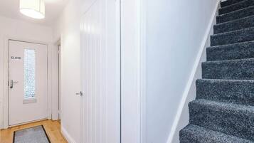 Een trap met beklede treden, een witte deur met een 'CLOSE' bordje en een lamp erboven.