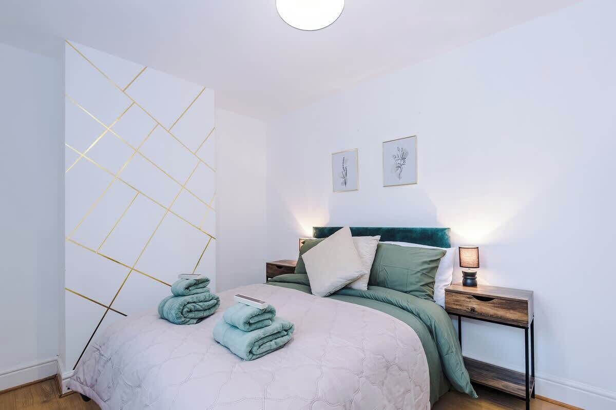 Ein Schlafzimmer mit einem Bett, einem Nachttisch, einer Wand mit geometrischem Muster und zwei gerahmten Bildern.