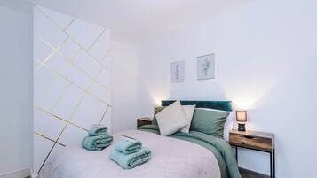 Ein Schlafzimmer mit einem Bett, einem Nachttisch, einer Wand mit geometrischem Muster und zwei gerahmten Bildern.