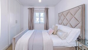 Una camera da letto con un letto, un comodino, un armadio e una finestra con tende.