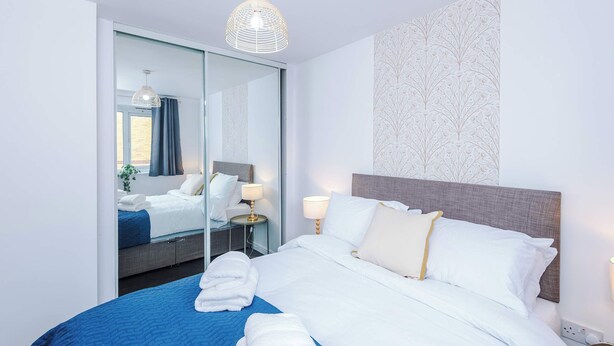 A hotel room with a bed, bedside lamps, a mirror, and a view of the outside. - Sleeps 5 Near Manchester Centre Free Parking (Greater Manchester)