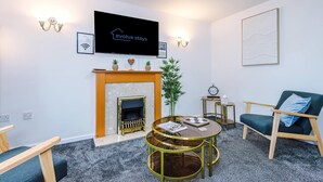A modern living room with a fireplace, a television, a round coffee table, and a comfortable seating area. - Sleeps 5 Near Manchester Centre Free Parking (Greater Manchester)