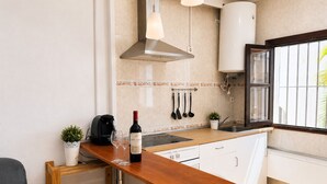 A compact kitchen with a wooden countertop, a stainless steel range hood, a coffee maker, and a wine bottle. - Brisa de Punta Lara Studio in Nerja (Nerja)