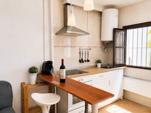 A compact kitchen with a wooden countertop, a stainless steel range hood, a coffee maker, and a wine bottle. - Brisa de Punta Lara Studio in Nerja (Nerja)