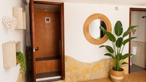 An open door leading to a bathroom with a stone wall, a mirror, and a potted plant. - Brisa de Punta Lara Studio in Nerja (Nerja)