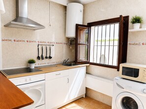 A compact kitchen with a stove, sink, microwave, and washing machine. - Brisa de Punta Lara Studio in Nerja (Nerja)