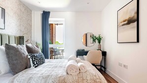 Habitación de hotel moderna con una cama grande, un escritorio, una silla, un espejo y vistas al exterior.