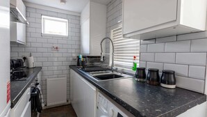 Una cocina compacta con lavadora integrada, un lavabo y una ventana.