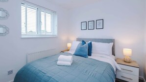 Camera da letto con un letto, comodini, una finestra e decorazioni alle pareti.