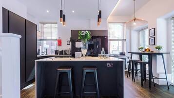 A modern kitchen with a central island, bar stools, pendant lighting, and a view of the city.