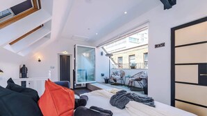 Ett modernt hotellrum med en säng, kuddar, ett litet bord, en stol och en balkong med utsikt.