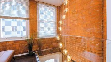 A room with brick walls, a bench, a potted plant, and hanging light fixtures.
