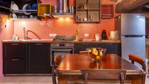 Uma cozinha com mesa de madeira, uma fruteira e uma geladeira de aço inoxidável.